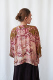 Woman wearing a patterned blouse with a white curtain background