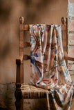 Decorative blanket with animal pattern draped over a wooden chair against a rustic wall.